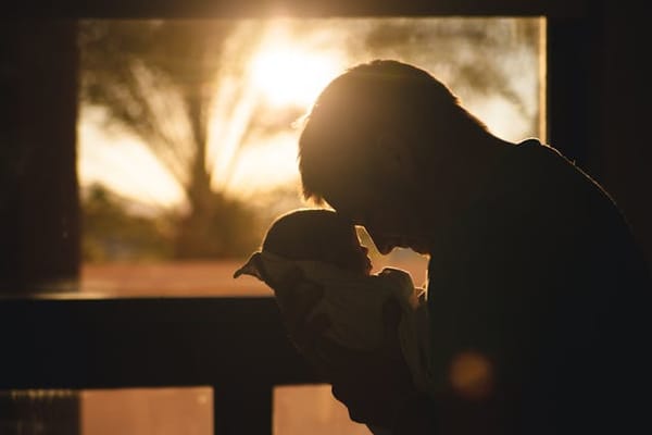 A father holding a baby, touching foreheads.